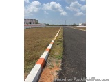 The image shows a long, straight road with a white and orange striped barrier on one side. The barrier is made of concrete an...