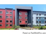 The image shows a modern building with a red and grey exterior. The building has multiple floors and is located in a resident...
