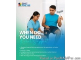 The image shows a young man sitting on a chair with a crutch in his hand. He is wearing a blue tank top and shorts and appear...