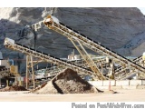 The image shows a large conveyor belt in a quarry. The belt is made of metal and is attached to a large metal structure with...