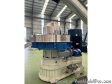 The image shows a large industrial machine inside a warehouse. The machine is white in color and has a cylindrical shape with...