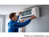 In this image, we can see a young man wearing a blue uniform, working on an air conditioning unit. He is standing in front of...