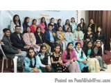 The image shows a group of people posing for a group photo on a stage. There are around 20 people in the photo, all dressed i...