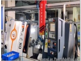 The image shows a large industrial machine, specifically a CNC (Computer Numerical Control) machine, in a workshop. The machi...