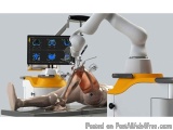 The image shows a medical examination table with a robotic arm on top of it. The robotic arm is white and has a long arm with...