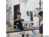 The image shows two young men standing in front of a counter in a store. They are both wearing blue shirts and appear to be i...