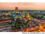 The image is an aerial view of a city at sunset. The city is densely populated with colorful buildings and temples. The sky i...