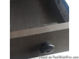 The image shows a close-up of a drawer with a black knob on it. The drawer appears to be made of wood and has a rectangular s...