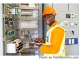 The image shows a young African-American man wearing an orange hard hat and safety vest, standing in front of an electrical p...