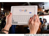 The image shows a person holding an iPad in their hands. The iPad is white and has the Google logo on the screen. The person'...