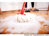 The image shows a person cleaning a wooden floor with a red mop. The mop has a white bristled head and a red handle. The floo...