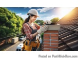 The image shows a young woman wearing a hard hat and overalls, working on a brick chimney. She is holding a brick mortar and...
