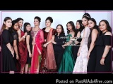 The image is a group photo of a group of women posing together. They are all dressed in traditional Indian attire, with some...
