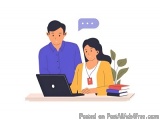 The image shows a man and a woman sitting at a desk with a laptop in front of them. The man is wearing a blue shirt and the w...