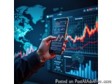 The image shows a person's hand holding a smartphone in front of a large screen with various graphs and charts on it. The bac...