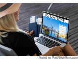 The image shows a woman sitting in an airplane seat with a laptop in front of her. She is wearing a black dress and a straw h...