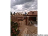 The image shows a construction site of a house under construction. The roof of the house is made of red tiles and there are w...