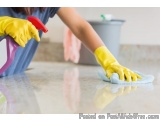The image shows a person's hand wearing yellow rubber gloves and using a spray bottle to clean a kitchen countertop. The pers...