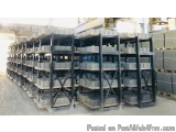The image shows a large warehouse with multiple rows of black metal shelves. The shelves are arranged in a neat and orderly m...