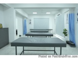 The image shows a modern and minimalist room with white walls and flooring. There are three long, rectangular tables with bla...