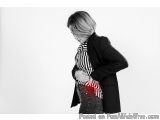 The image is a black and white photograph of a woman standing with her back to the camera. She is wearing a black blazer over...