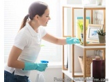 In this image, we can see a young woman wearing a white polo shirt and blue rubber gloves. She is standing in front of a wood...