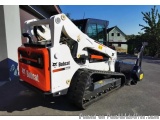 The image shows a Bobcat skid steer loader parked in a parking lot. The loader is white and orange in color with the Bobcat l...