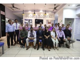The image shows a group of people posing for a group photo in front of a sign that reads "Globus Hospital". The group is arra...
