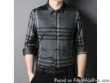 The image shows a man wearing a black and grey plaid button-down shirt. The shirt has a collar and long sleeves. The plaid pa...