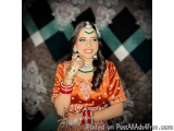 The image is a portrait of a beautiful Indian woman wearing traditional Indian attire. She is wearing a red and gold lehenga...