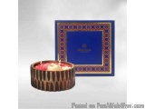 The image shows a small round cake with a blue box. The box is rectangular in shape and has a gold border with an intricate p...