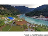 The image is an aerial view of a beautiful resort with a stunning view of the river and mountains in the background. The reso...