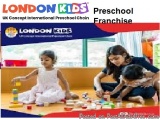 The image shows a mother and her two young daughters playing with colorful building blocks on the floor in a classroom. The m...