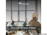 The image shows a group of three people sitting around a desk in an office space. The room has large windows that let in natu...