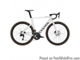 The image is of a white Cannondale Super Record road bike. The bike has a sleek design with a black saddle and handlebars. Th...