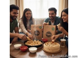 The image shows a group of four young people, two men and two women, sitting around a wooden table in a living room. They are...