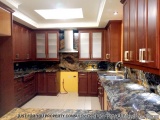The image shows a modern kitchen with wooden cabinets and granite countertops. The kitchen has a large island with a sink and...