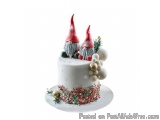 The image is of a three-tiered cake with a white base. The cake is decorated with red and green sprinkles and gold ornaments....