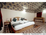 The image shows a bedroom with a large bed in the center. The bed is made up with white linens and black pillows, and there a...