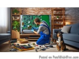 The image shows a man in a blue overalls and a blue shirt working on a large TV screen in a living room. He is kneeling on th...