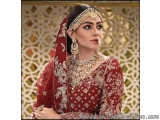 The image is a portrait of a beautiful Indian bride. She is wearing a traditional red lehenga with intricate gold embroidery...