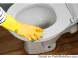 The image shows a person's hand wearing a yellow rubber glove cleaning a white toilet bowl. The person is using a sponge to c...