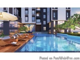 The image shows a modern apartment complex with a large swimming pool in the center. The pool is rectangular in shape and has...