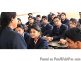 The image shows a group of students sitting in a classroom. They are all wearing school uniforms and are sitting at desks. Th...