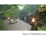 The image is a screenshot from a video game. It shows a car driving on a dirt road in a forested area. The road is surrounded...