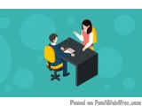 The image shows a man and a woman sitting at a desk in an office. The man is sitting on a yellow office chair and the woman i...