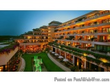 The image shows a luxurious hotel building at night. The building is a two-story structure with multiple floors and balconies...