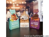 The image shows three small gift bags with different designs on them. The bags are placed on a table in a restaurant or cafe....