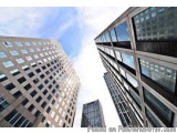 The image shows two tall buildings with glass windows. The buildings appear to be modern and high-rise, with a sleek design....