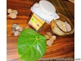 The image shows a wooden table with a small glass jar with a white lid and a label on it. The jar is filled with a yellow-col...